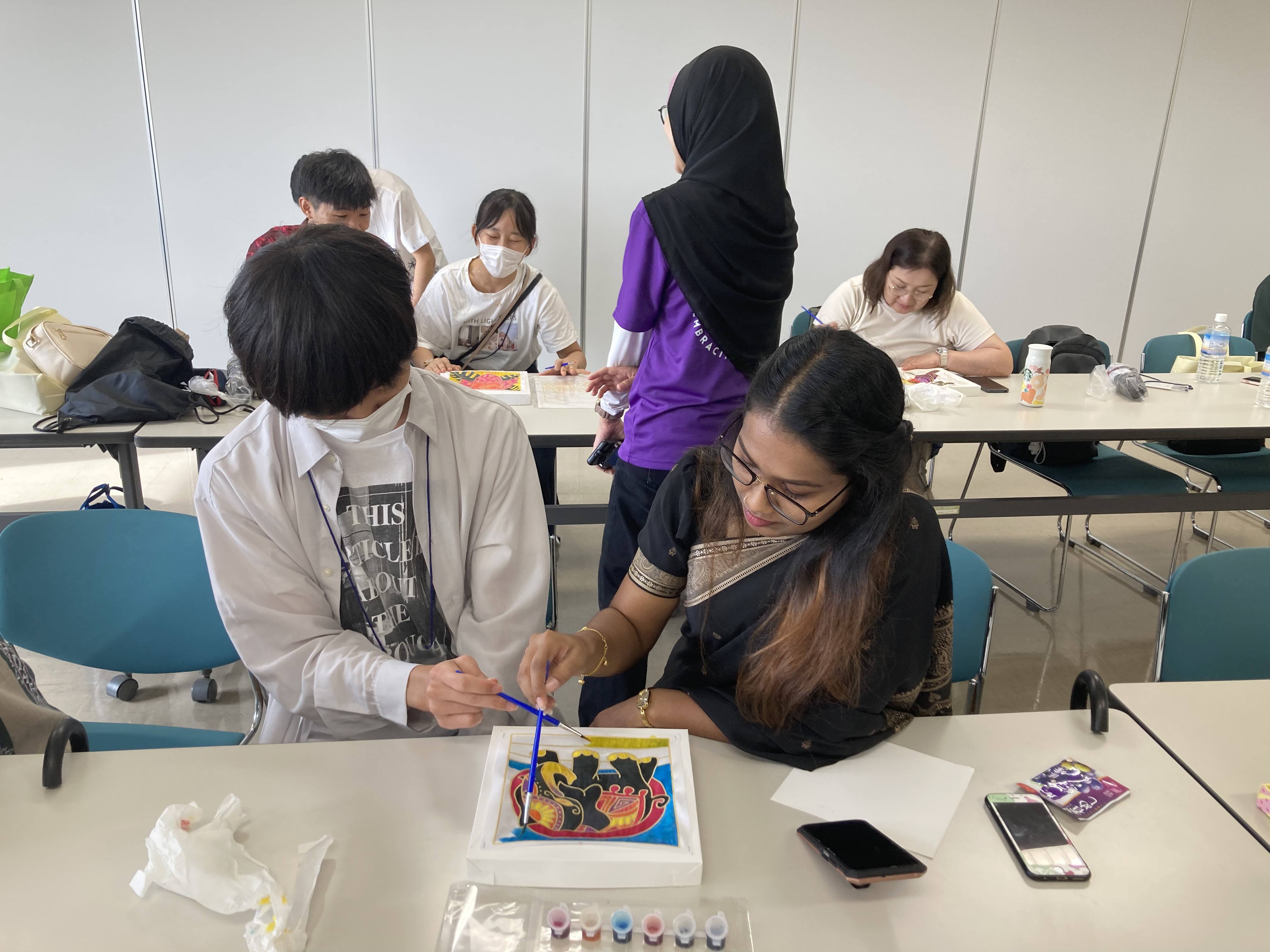 マレーシアの伝統工芸「バティック（ろうけつ染）」の色塗りを体験。大阪工業大学とマレーシアサインズ大学の学生がペアになり、一つの作品を制作しました。