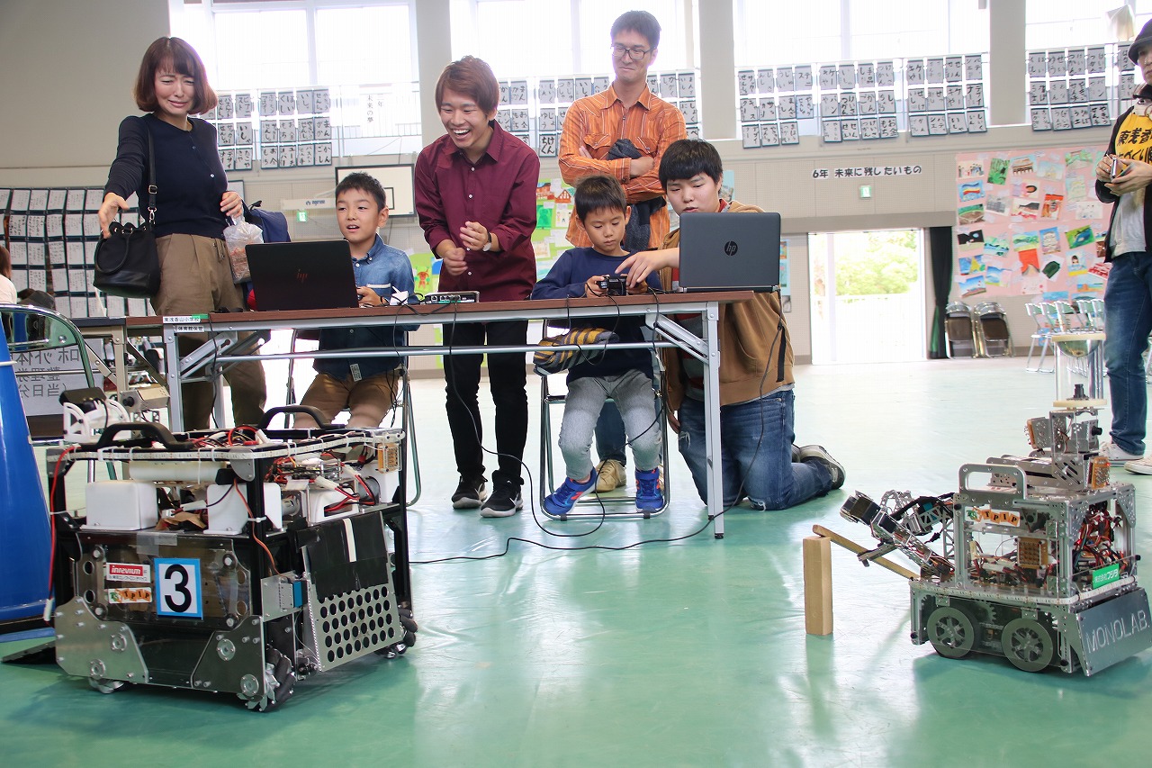 学生からレスキューロボットのレクチャーを受け、瓦礫パーツを撤去する児童ら