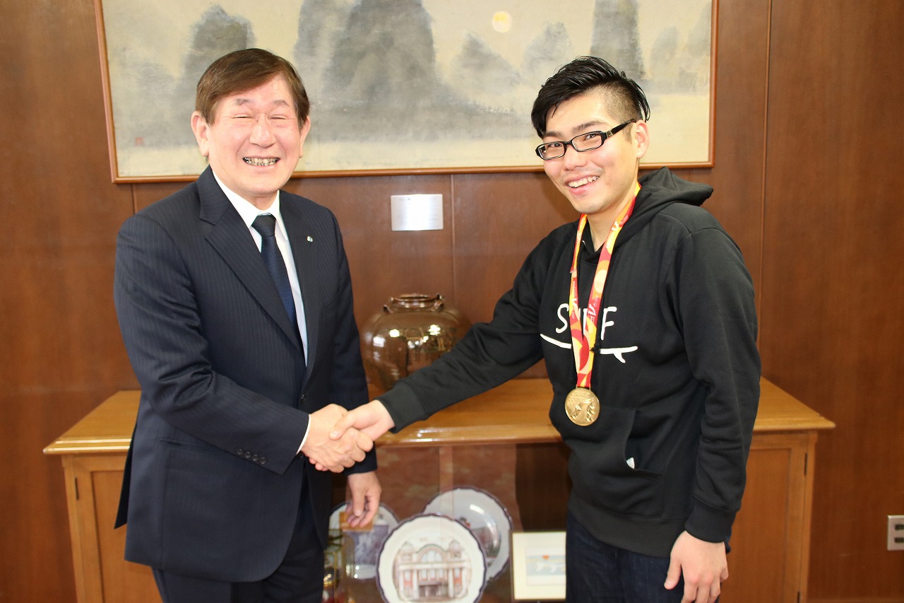 世界の舞台での活躍を誓い西村学長と固い握手を交わす川口氏（写真右）