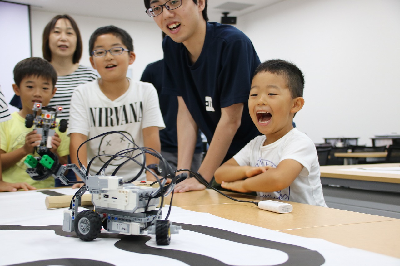 プログラミングとおりに走るロボットカーを見て、喜びの声を上げる子供たち