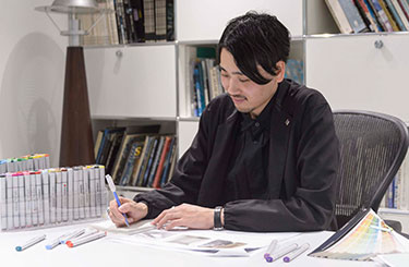 写真：机に向かって何かを書く林原さん