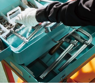 写真：台車に備え付けられた工具箱から工具を取る手元