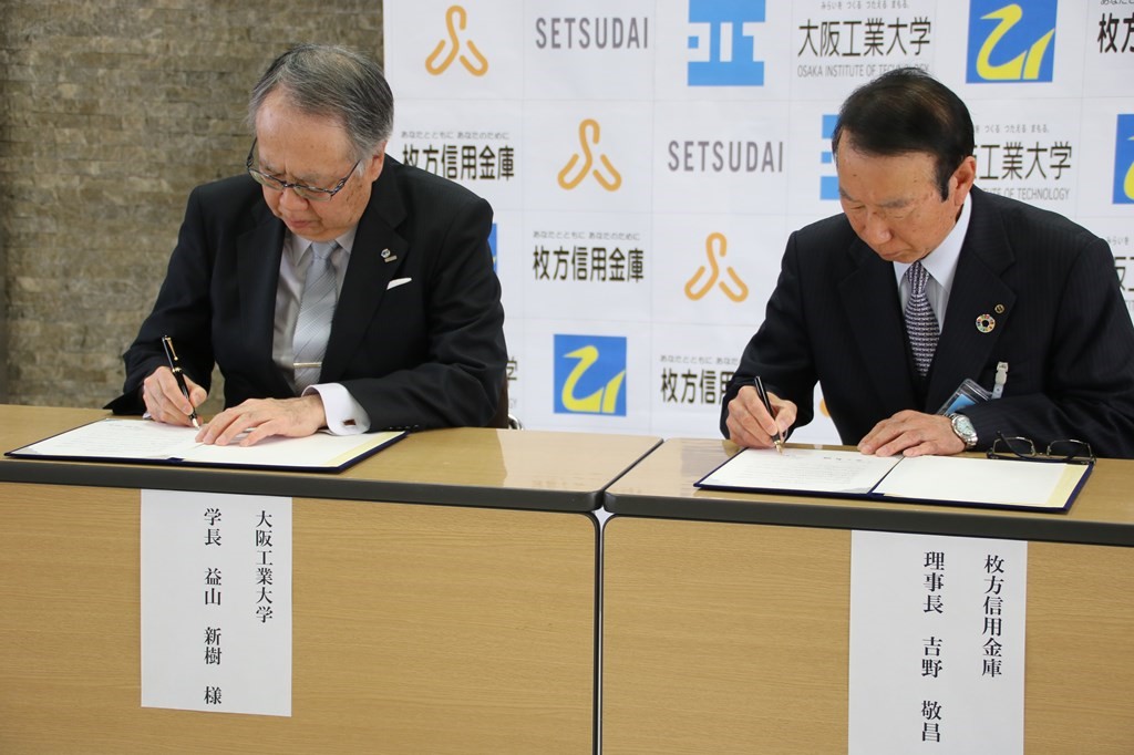 協定書にサインをする益山新樹学長（左）と吉野敬昌理事長