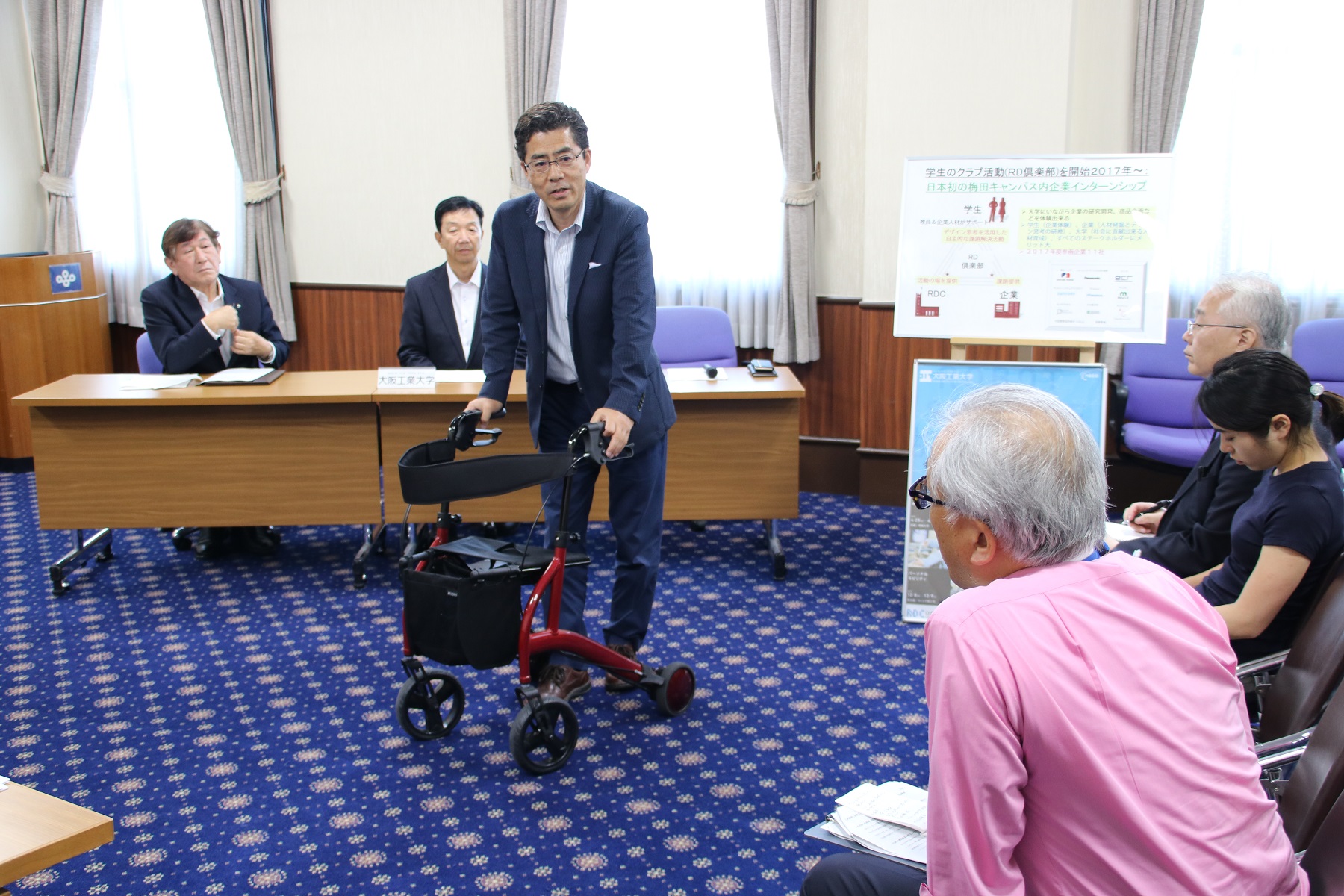 本学ロボティクス＆デザインセンタ―長の本田幸夫教授が高齢者向けの歩行アシストカートを紹介