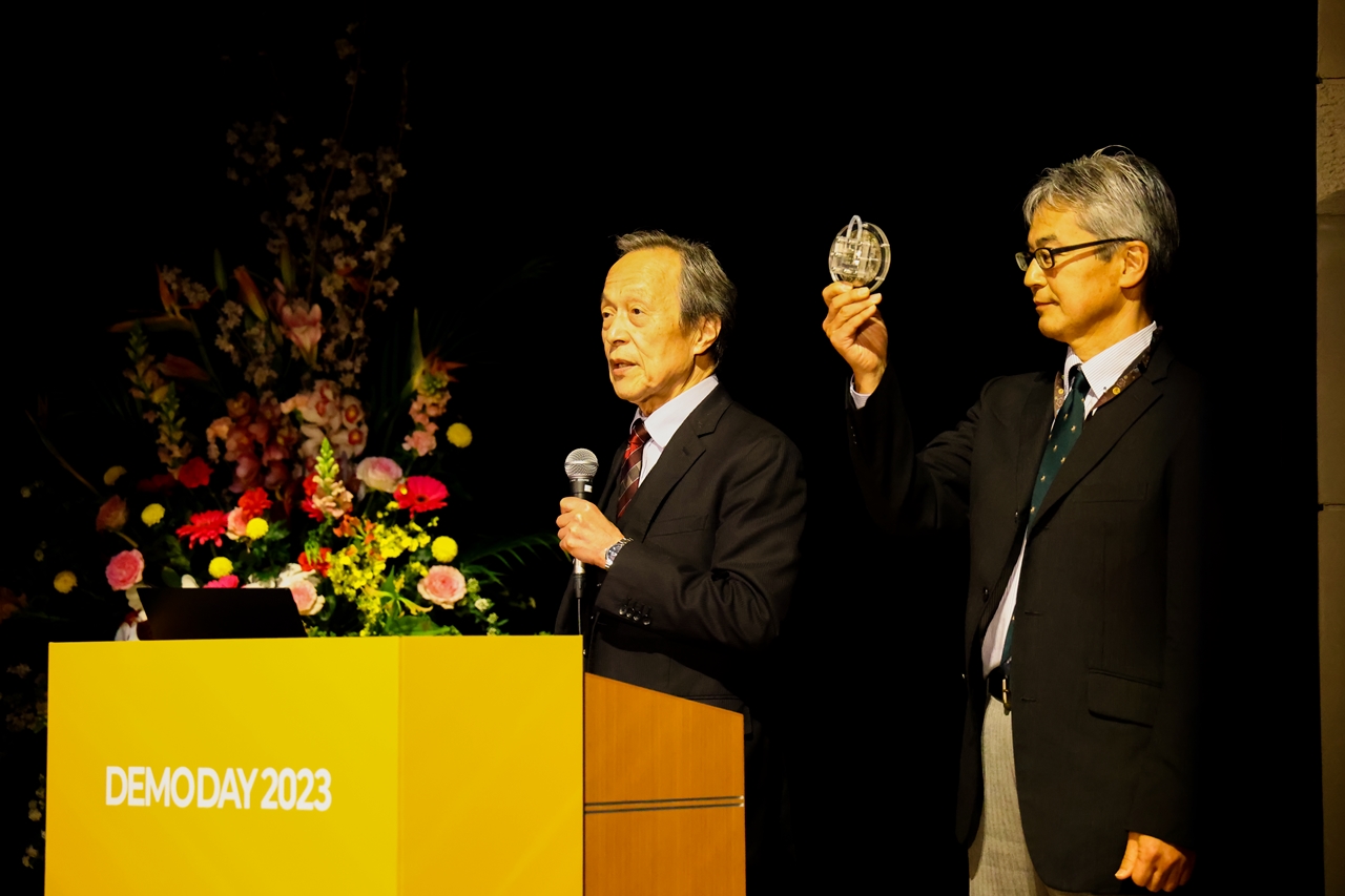 金藤客員教授（左）は装置のサンプルも示しながら発表した