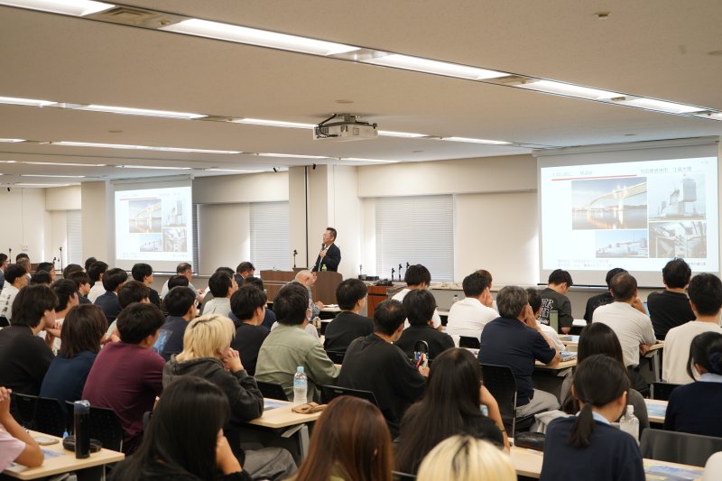 同社が取り組む施工の省人化に向けた技術等を紹介する三田氏と聴講者たち