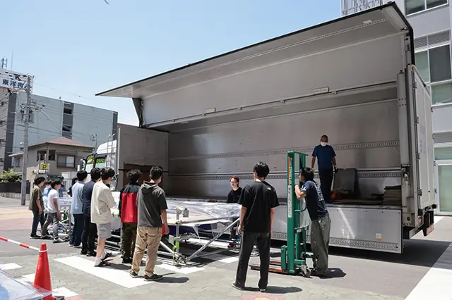 写真：学内の駐車場で大型のトラックにソーラーカーを載せる選手たち